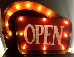 an open sign is lit up with lights on it's sides and the words open are written in white letters