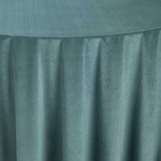 a round table covered in a light blue velvet cloth with an oval design on the top