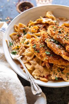 a white bowl filled with pasta covered in sauce and chicken cutlets, topped with parmesan cheese