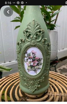 a green vase sitting on top of a wicker table