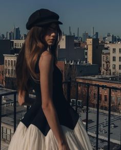 a woman in a black and white dress is standing on a balcony looking at the city