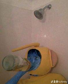 a person in a yellow and blue costume drinking from a water bottle