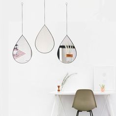 three tear shaped mirrors hanging from the ceiling above a desk with a chair and plant