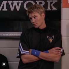 a young man with his arms crossed standing in front of a sign that says work