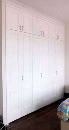 a bedroom with white closets and wooden floors