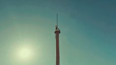 the sun shines brightly behind a tall tower with a flag on it's top