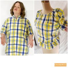 a woman wearing a yellow and blue plaid shirt with her hands in the air while standing next to a mannequin