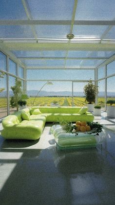 a living room filled with lots of furniture under a glass roof over looking the ocean