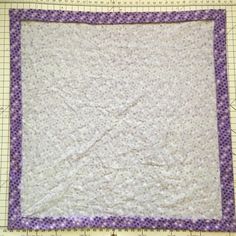 a quilted square with purple trim on it