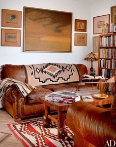 a living room filled with brown leather furniture and bookshelves on the wall above