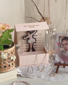 an open box on a table with flowers and other items around it that include jewelry