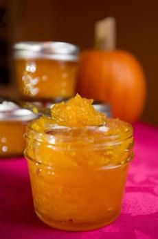 a jar filled with orange marmalade sitting on top of a pink table cloth