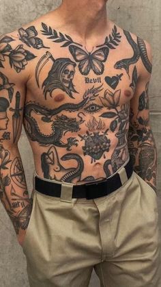 a man with lots of tattoos on his chest and arms is standing in front of a brick wall