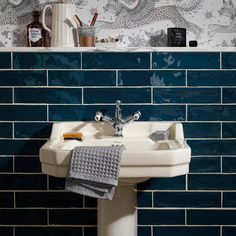 a white sink sitting next to a blue tiled wall