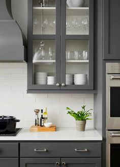 a kitchen with gray cabinets and white counter tops