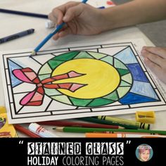 stained glass holiday coloring pages with colored pencils and crayons on the table