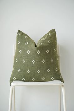 a green pillow sitting on top of a white chair