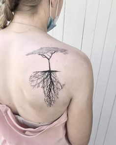 a woman with a tree tattoo on her back shoulder and the roots are all connected together