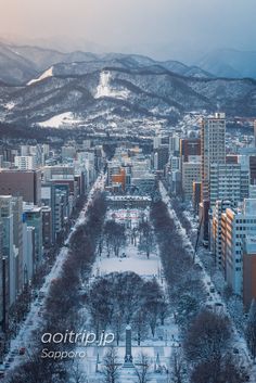 an aerial view of a city with snow on the ground and mountains in the background