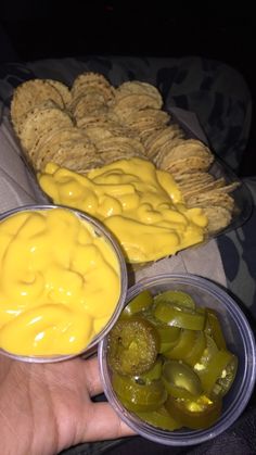 two plastic containers filled with pickles and crackers