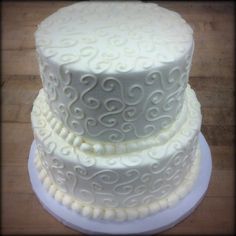 three tiered white wedding cake sitting on top of a wooden table next to each other