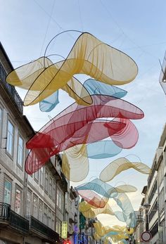 a street filled with lots of tall buildings and colorful art hanging from the side of it