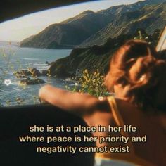 a woman sitting in a car looking out at the ocean and mountains with a quote written on it