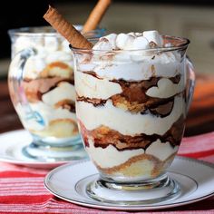 two glasses filled with dessert sitting on top of a table