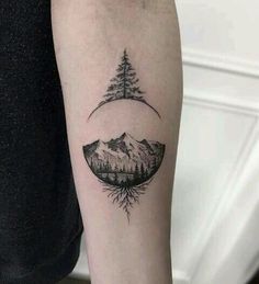 a person with a tattoo on their arm that has trees and mountains in the background