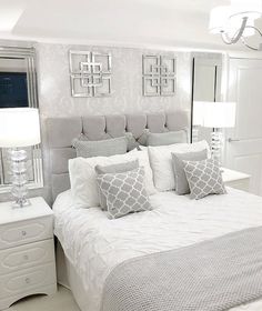 a bedroom with white bedding and silver accents