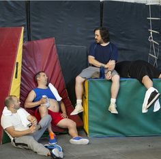 three men sitting on top of different colored structures