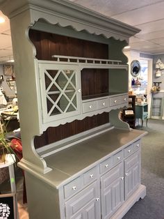 a white china cabinet in a store with lots of furniture on it's sides