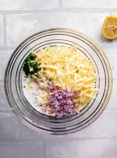 cheese, onions and broccoli in a glass bowl next to a lemon slice