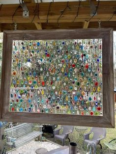 a framed glass art piece hanging from a wooden frame over a table with chairs and tables in the background