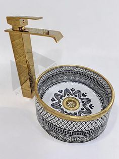 a sink with a gold faucet and decorative design on the bowl is shown in front of a white background