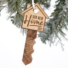 a wooden ornament hanging from a tree with the words our new home on it