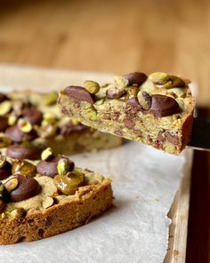 there is a piece of cake that has pistachios on it and chocolate chips