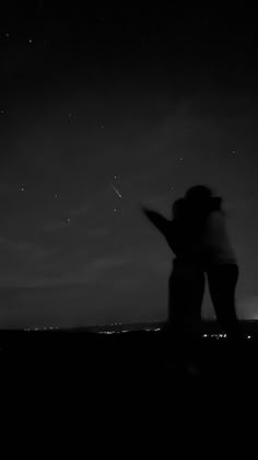 two people standing next to each other under a night sky with stars in the background