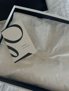 an open box with a white and black print on it, sitting on a bed