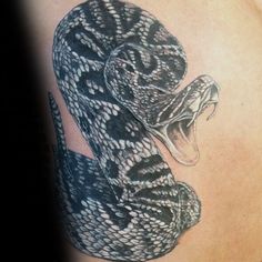 a black and white snake tattoo on the back of a woman's shoulder with it's mouth open