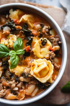 a white bowl filled with pasta and spinach soup