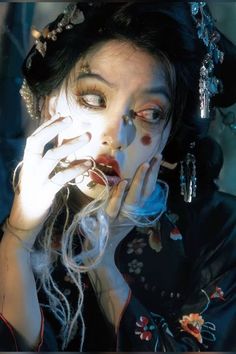 a woman with makeup on her face and hands in front of her face