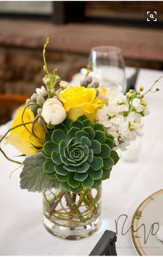 a vase filled with yellow and white flowers on top of a table next to a plate