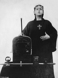 a black and white photo of a person with a cross on their head standing next to a suitcase