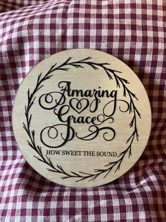 a wooden plaque that reads amazing grace how sweet the sound on top of a checkered blanket