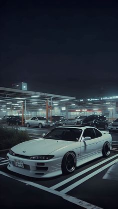 a white car parked in front of a gas station at night with the lights on