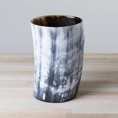 a black and white cup sitting on top of a wooden table