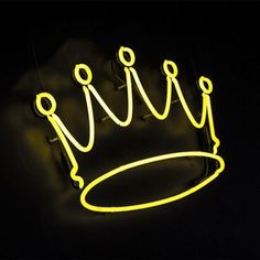 a neon sign with a crown on it in the dark, lit up by yellow light