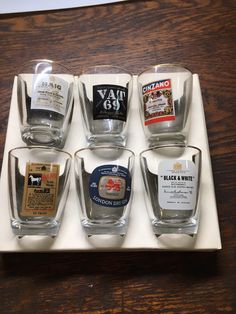 four shot glasses sitting on top of a white tray filled with different types of liquor