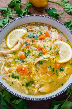 a bowl of chicken and rice soup with lemons, parsley and parsley